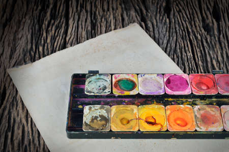 Closeup of messy, used water color paint box on dirty paperの写真素材