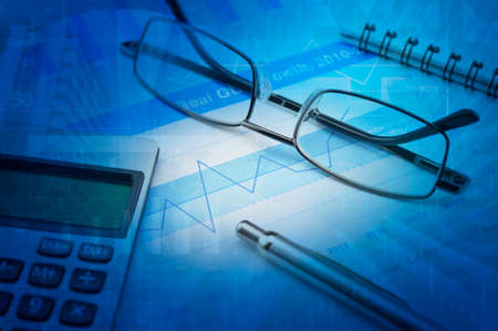 Gasses pen and calculator on financial chart and graph, accounting backgroundの写真素材