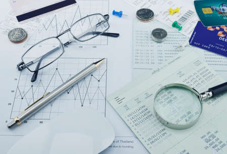 Magnifying glass, pen, account book, glasses, coin on paper chart, saving concept