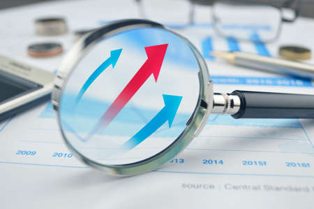 Rising red and blue arrow on magnifying glass, success concept