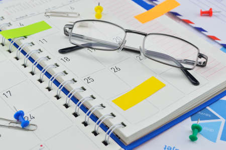Monthly planner with glasses, pin and post it on paper graphの写真素材