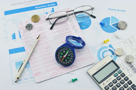 Compass pen glasses coin and calculator on saving book investment conceptの写真素材