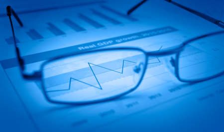 Glasses on blue financial chart and graph blue tone success conceptの写真素材