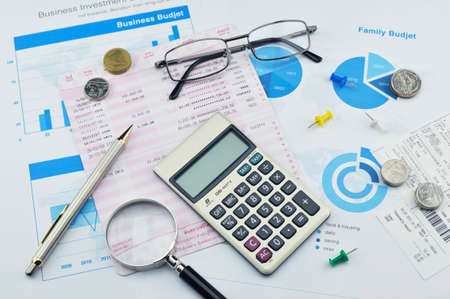 Magnifying glass pen calculator and coin on graph paper saving conceptの写真素材
