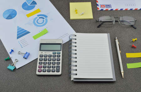 Pen book calculator glasses and financial chart and graph on tableの写真素材