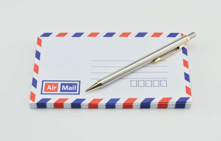 Stack of air mail envelopes with pen on white backgroundの写真素材