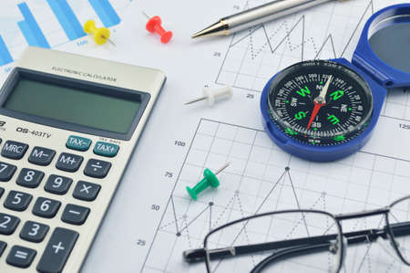 Blue compass, calculator, pen, pin and glasses on graph paper, success concept