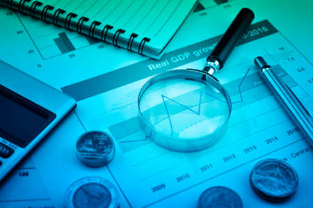 Magnifying glass, pen and calculator on financial chart and graph, accounting backgroundの写真素材