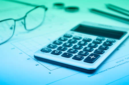 Calculator button plus, glasses coin pencil and mouse on graph paper backgroundの写真素材