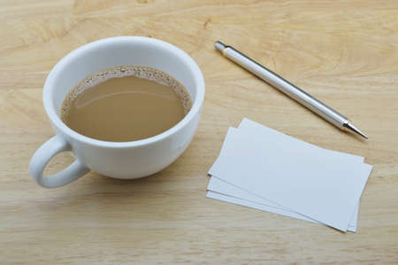 Blank card with coffee cup and pencil on wooden table