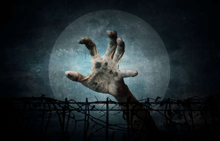 Hand over metal fence with dry leaves over dark sky and moon, grunge style, Halloween conceptの写真素材