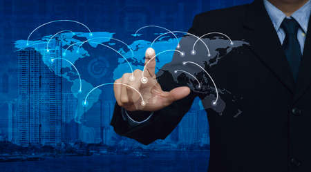 Businessman pushing world network connection center button on city tower and business graph, Elements of this image furnished by NASAの写真素材