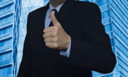 Businessman with thumbs up on city tower backgroundの写真素材