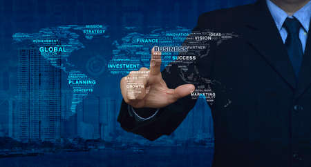 Businessman pushing business words map shape on city tower and business graph, Elements of this image furnished by NASAの写真素材