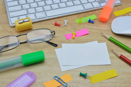 Paper notes, colorful sticky notes, pencil, clip, glasses, mouse and keyboard on wooden tableの写真素材