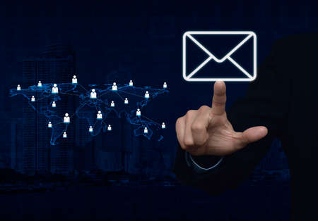 Businessman hand pushing email icon with light blue world map connection on city tower, Elements of...