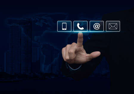 Businessman pressing telephone, mobile phone, at and email buttons over map and city tower, Customer support concept.の写真素材