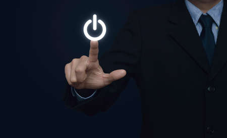 Businessman pressing power button on blue backgroundの写真素材