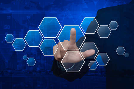 Businessman hand pushing blank modern virtual technology screen on map, graph and city towerの写真素材