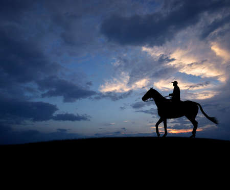 Man riding horse over sunset skyの写真素材