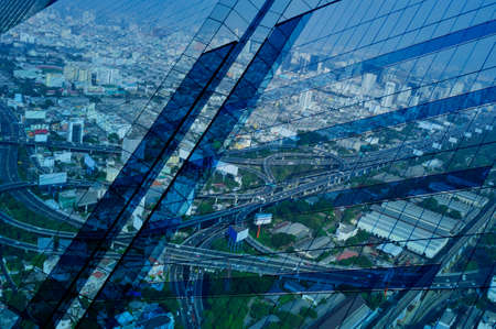 Reflect of aerial view of cityscape expressway and highway on window glass tower, blue tone, Bangkok Thailandの写真素材