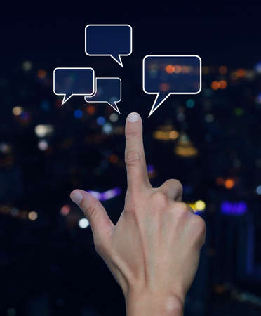 Hand point to social chat sign and speech bubbles over blur light city tower background, Social...