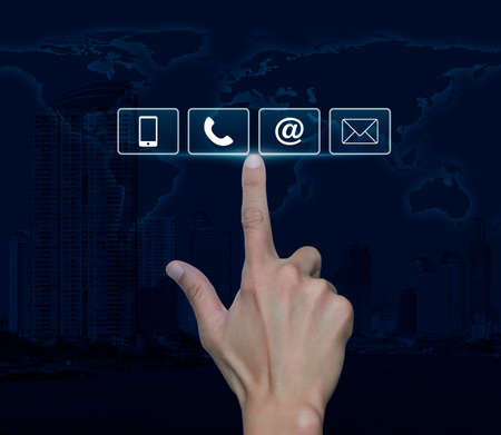 Hand pressing telephone, mobile phone, at and email buttons over map and city tower, Customer...