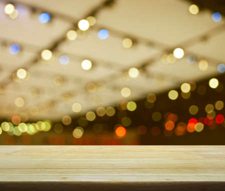 Empty wooden table over defocused light and shadow of shopping mall, for product display