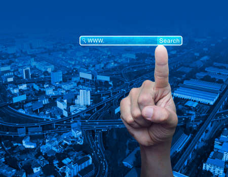 Hand pressing search www button over city tower background, Searching system and internet conceptの写真素材
