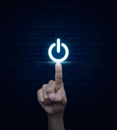 Hand pressing power button over computer binary code blue background