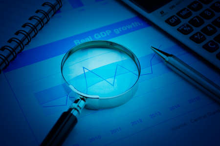 Magnifying glass, pen and calculator on growth financial chart and graph, success business conceptの写真素材