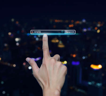 Hand pressing search www button over blur light city tower background, Searching system and internet conceptの写真素材