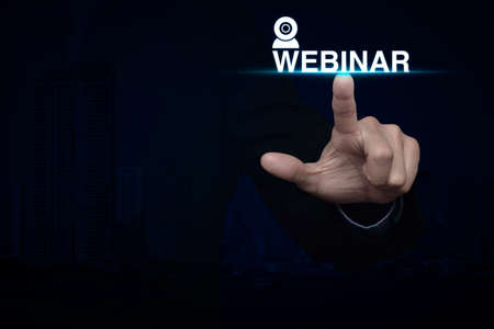 Businessman pressing webinar icon over city tower background, Seminar online conceptの写真素材