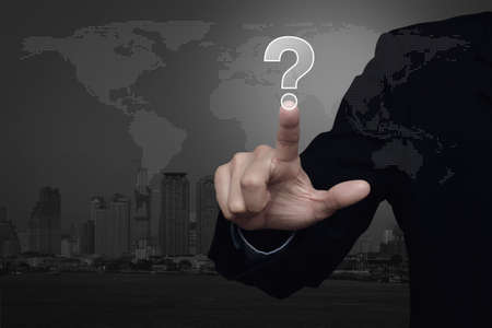 Businessman pressing question mark sign icon over black and white dotted world map with city tower background, Customer support conceptの写真素材