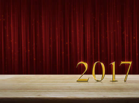Happy new year 2017 gold metal text on wooden table over red curtain with sparkle glitter