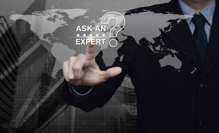 Businessman pressing ask an expert with star and question mark sign icon over black and white world map and city tower with financial graph, Elements of this image furnished by NASAの写真素材
