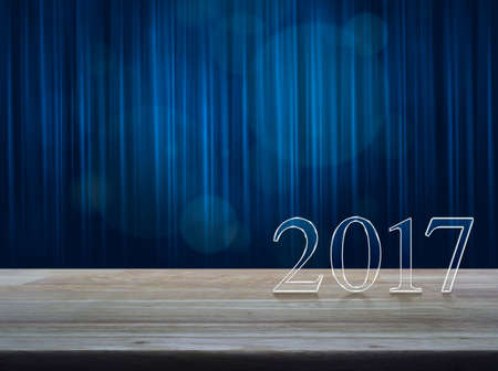 Happy new year 2017 text on wooden table over blue curtain with spot lightの写真素材