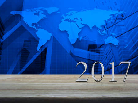 Happy new year 2017 silver metal text on wooden table over world map and city tower background, Elements of this image furnished by NASAの写真素材