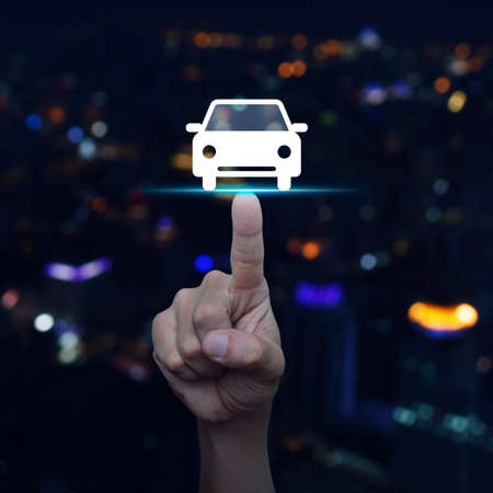 Hand pressing car front view flat icon over blur colourful night light city tower, Business service car conceptの写真素材