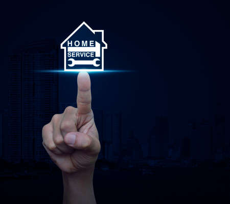 Hand pressing hammer and wrench with house icon over city tower background, Home service conceptの写真素材