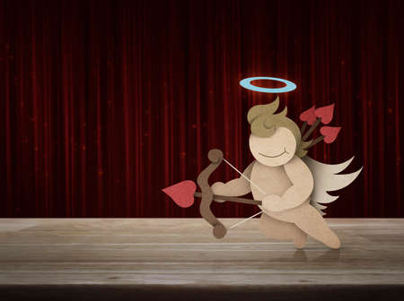 Cupid recycle paper craft on wooden table over red curtain with sparkle glitter, Valentines day conceptの写真素材
