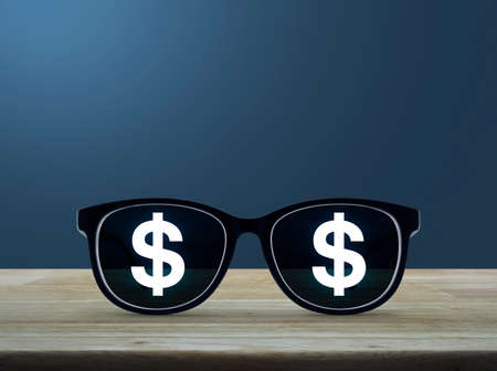 Dollar currency icon with eye glasses on wooden table over light blue gradient background, Business success conceptの写真素材