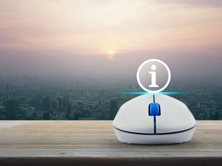 Information sign icon with wireless computer mouse on wooden table over modern city tower at sunset, vintage style, Customer support conceptの写真素材