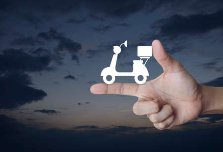 Motor bike icon on finger over sunset sky, Business delivery service conceptの写真素材