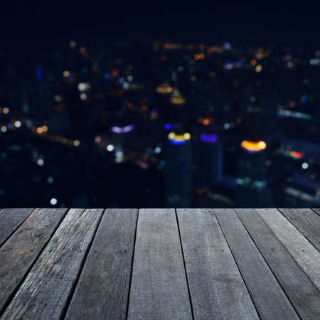 Empty old wood floor in front of blurred light city towerの写真素材