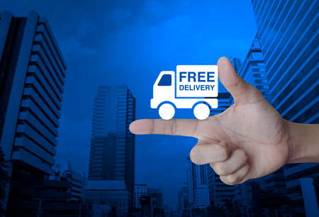 Free delivery truck icon on finger over modern office city tower, Transportation business conceptの写真素材