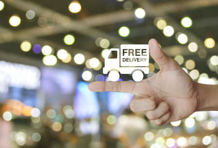 Free delivery truck icon on finger over blur light and shadow of shopping mall, Transportation business conceptの写真素材