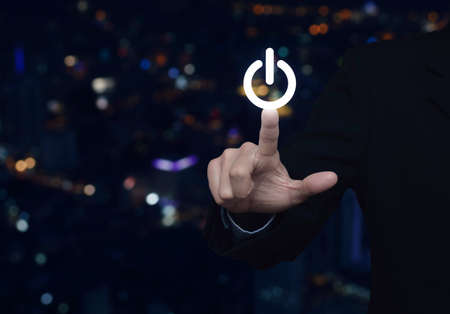 Businessman pressing power button over blur colorful night light city tower, Start up business conceptの写真素材