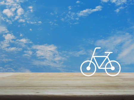 Bicycle flat icon on wooden table over blue sky with white clouds, Healthy lifestyle conceptの写真素材