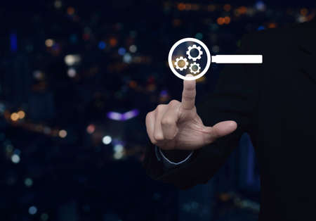 Businessman pressing seo flat icon over blur colorful night light city tower, Search engine optimization conceptの写真素材